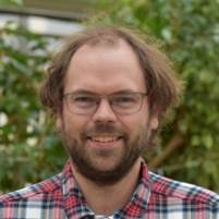 A person with glasses smiling

Description automatically generated