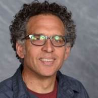 A person wearing glasses and a blue jacket

Description automatically generated